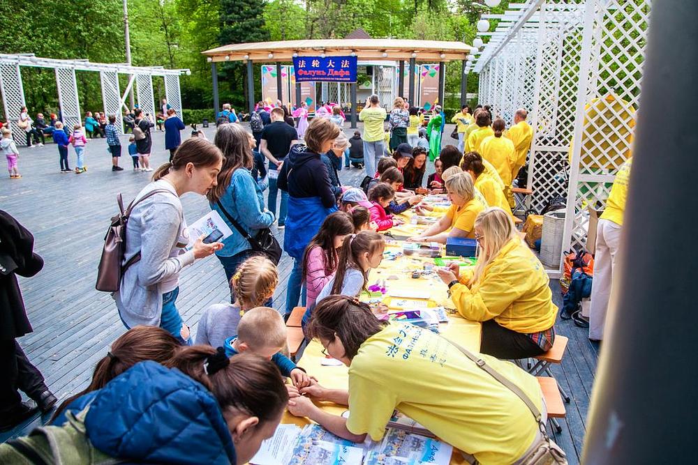 Falun Gong praktikanti pored pozornice uče djecu kako izrađivati papirnate lotose.