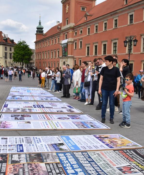 Turisti čitaju informacije o Falun Gongu.