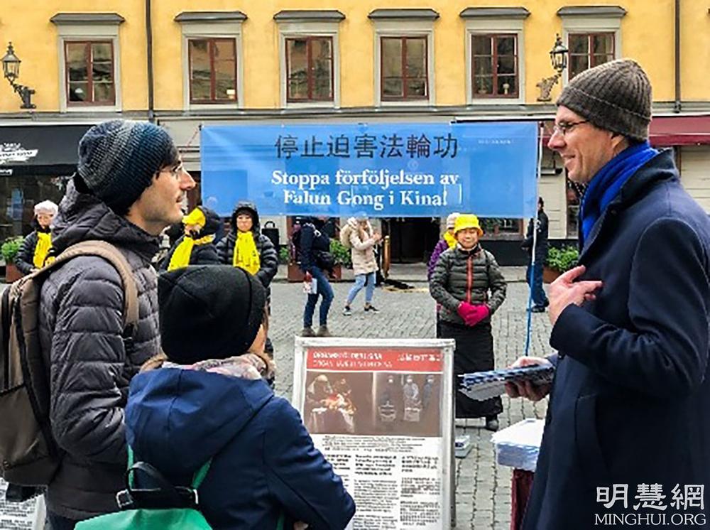 Praktikant (desno) razgovara sa prolaznicima o Falun Dafi ispred Muzeja Nobelove nagrade.