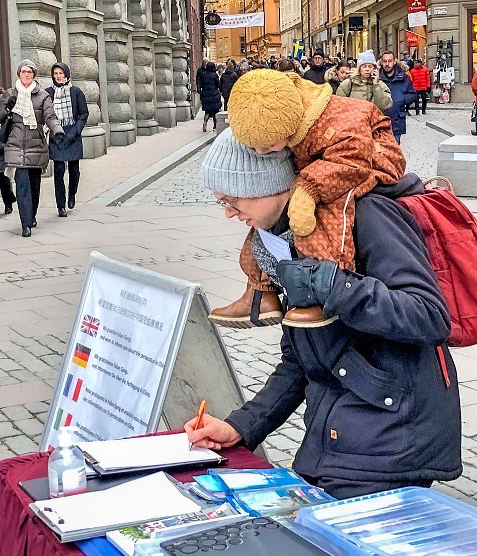 Prolaznik je razgovarao sa praktikantom kako bi saznao više o Falun Dafa, a zatim potpisao peticiju za zaustavljanje progona u Kini.