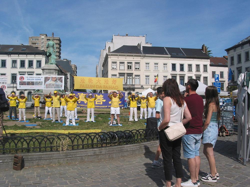 Ljudi razgovaraju sa praktikantima i slušaju govornike na skupu kako bi saznali više o Falun Dafa i progonu.