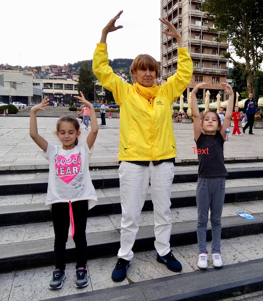 Dve devojčice uče drugu vežbu Falun Dafe, „Falun stojeći stav“ 