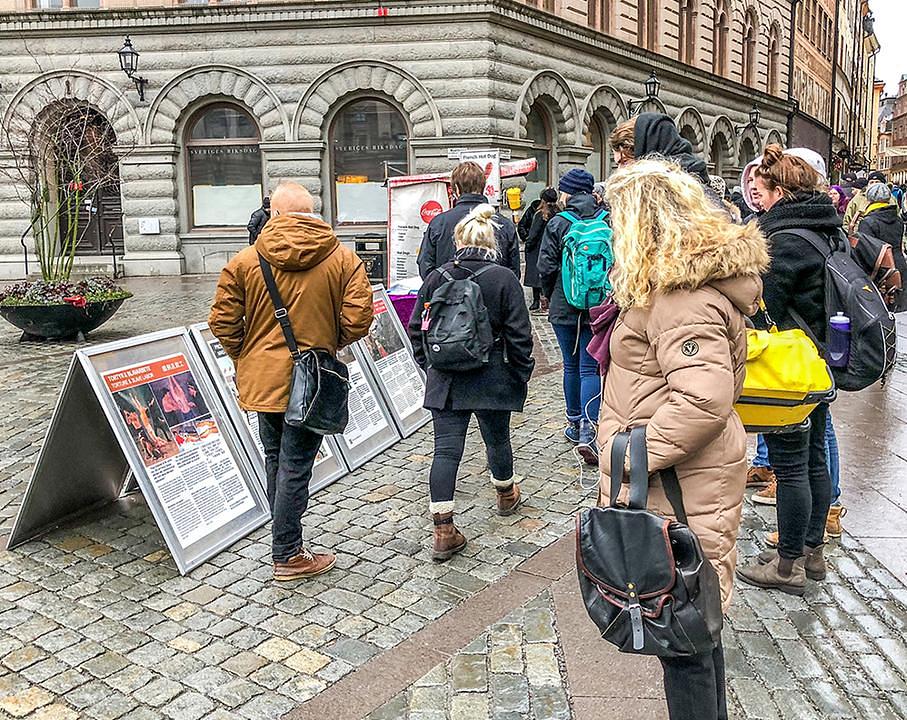 Turisti čitaju o Falun Gongu