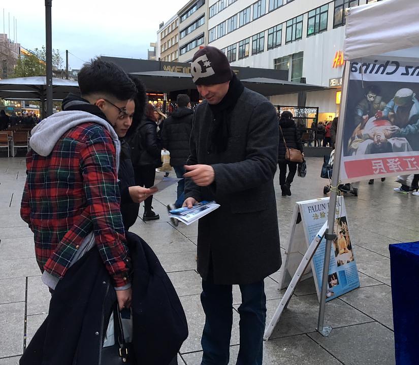 Praktikant Dima Guskov sa dva mladića razgovara o Falun Gongu.