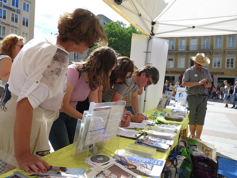 Ljudi potpisuju peticiju da bi  protestvovali protiv progona Falun Gonga u Kini.