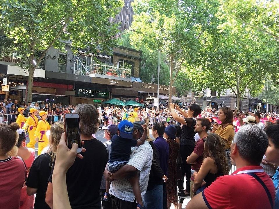 Gledaoci slikaju Falun Gong povorku.