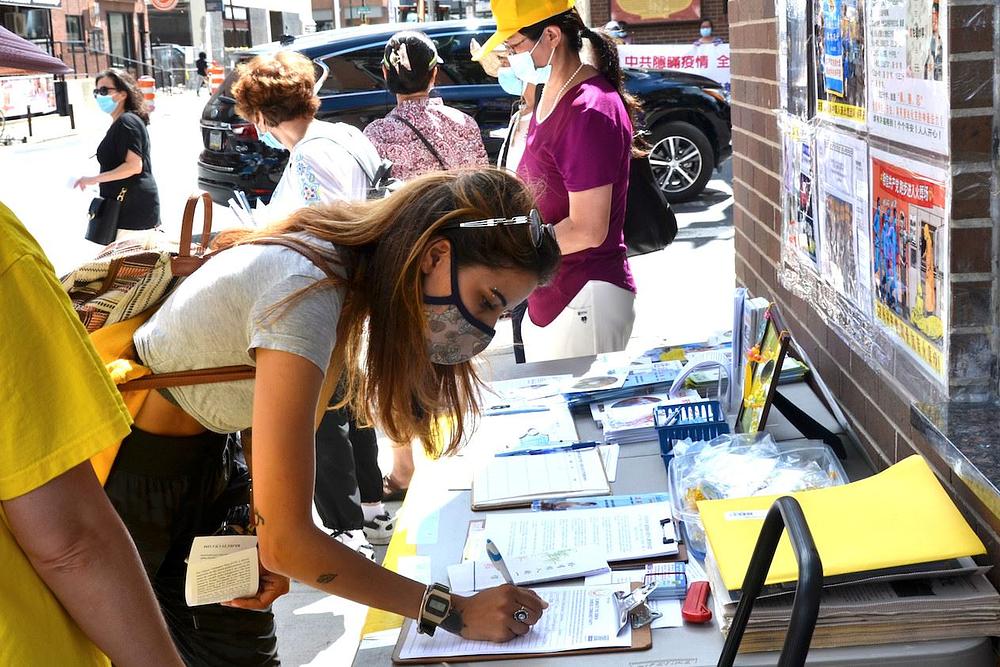 Prolaznici potpisuju peticiju kojom se osuđuje progon Falun Gonga i odbacuje KPK.
