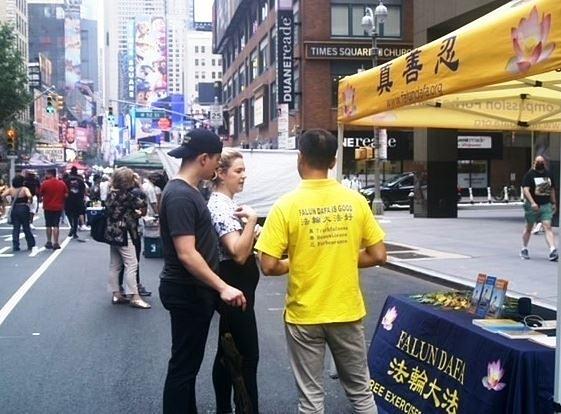 Michael (prvi lijevo) i njegova prijateljica Aryca (druga lijevo) slušaju dok im praktikant govori o Falun Dafa.