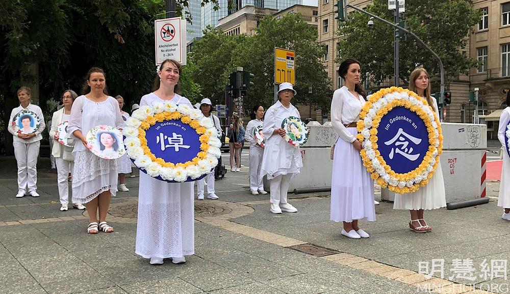 Praktikantice u bijeloj odjeći drže portrete kolega praktikanata koji su bili mučeni do smrti